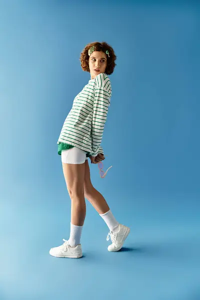 Eine junge Frau mit kurzen lockigen Haaren präsentiert ihr gewagtes Sommeroutfit, das Stil ausstrahlt. — Stockfoto