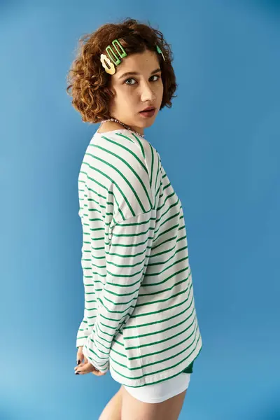 Curly-haired woman poses in a vibrant outfit against a blue backdrop. — стокове фото