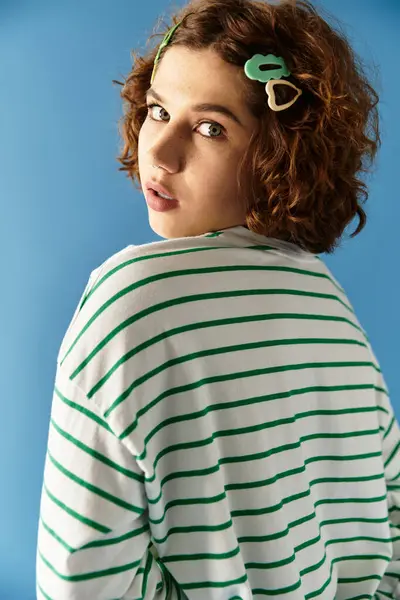 Eine junge Frau zeigt ihr lockiges Haar und ihr lebhaftes Outfit, während sie spielerisch in Sommermode posiert. — Stockfoto