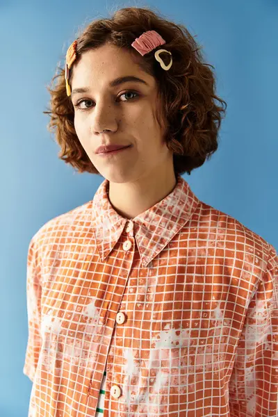 A young woman with curly hair poses confidently in a vibrant summer outfit against a blue backdrop. — Stock Photo