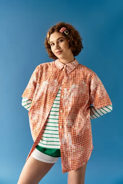A young woman poses confidently in a vibrant outfit against a blue backdrop, embodying summer style. — Stock Photo