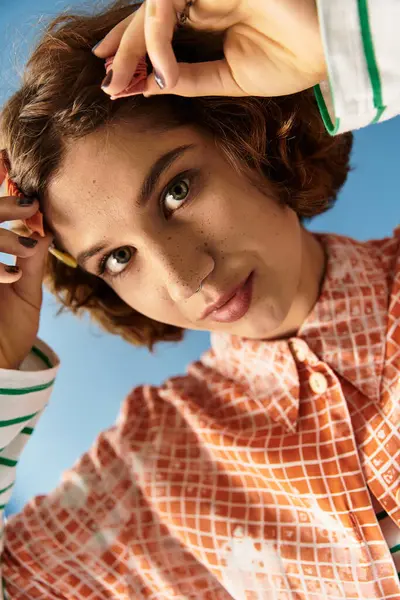 Young woman with curly hair showcases a vibrant outfit against a bright blue backdrop. — Stock Photo