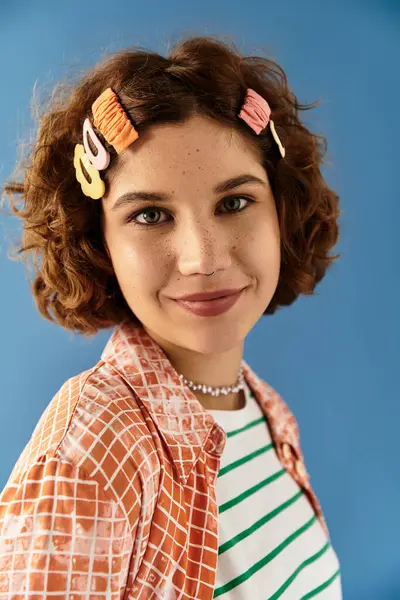 A young woman with short curls poses in a colorful outfit against a bright blue backdrop. — Stock Photo