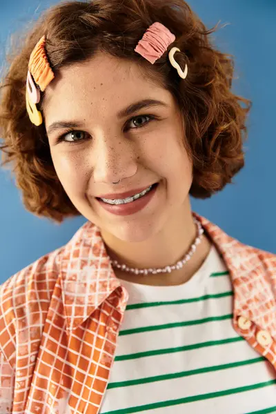 A young woman poses confidently in a vibrant outfit against a blue background. — Stock Photo
