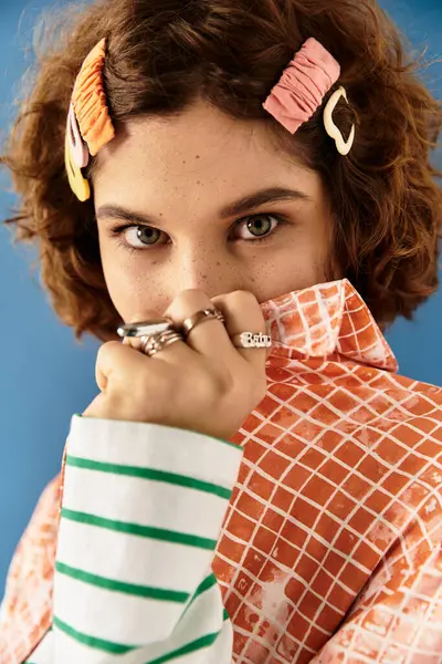 A young woman poses playfully in a colorful outfit against a blue backdrop. — Stock Photo