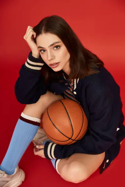 Dynamic woman poses confidently with a basketball in a vibrant setting, radiating style. — Stock Photo