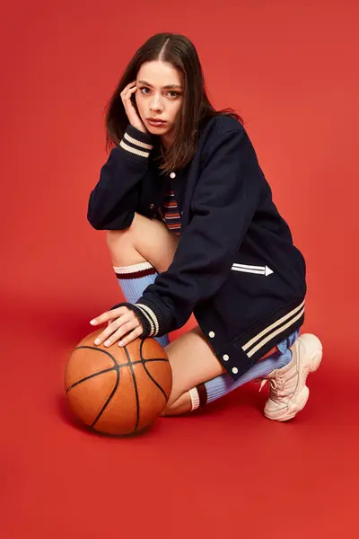 Vibrant and fashionable young woman squats with a basketball, exuding confidence and style. — Stock Photo