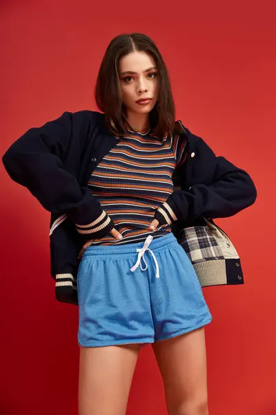 A young woman confidently showcases her unique style in vibrant attire against a bold backdrop. — Stock Photo