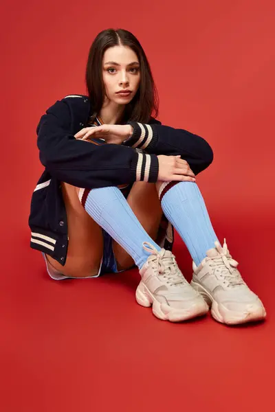 A stylish young woman displays her vibrant outfit and playful socks while seated. — Stock Photo