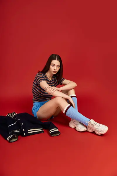 A young woman exudes confidence in colorful clothing while sitting on a vibrant backdrop. — Stock Photo