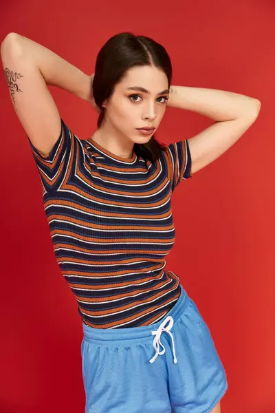 A young, stylish woman showcases her fashion sense in vibrant, striped clothing with confidence. — Stock Photo