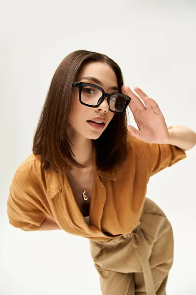 Young woman in fashionable attire strikes a pose with stylish glasses, exuding confidence and charm. — Stock Photo