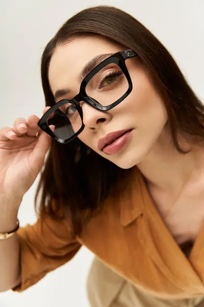 Embodying confidence, a young woman poses stylishly in fashionable attire and chic eyewear. — стокове фото