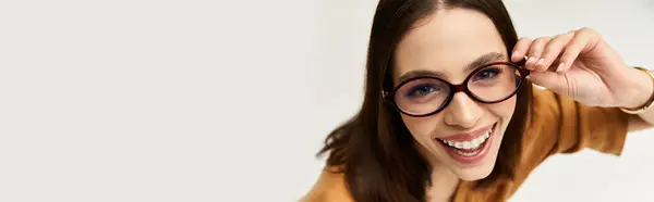 Encantadora joven muestra su look moderno mientras se ajusta juguetonamente las gafas y sonríe. — Stock Photo