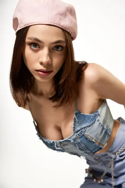Young woman in fashionable attire exudes charm and elegance, posing with flair in a studio. — стокове фото