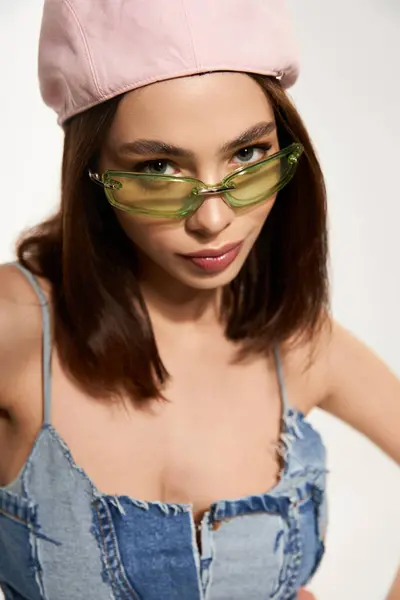 Young woman in fashionable denim outfit poses confidently with stylish accessories for summer vibes — стокове фото