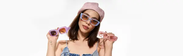 Young woman presents trendy eyewear while wearing fashionable attire against a bright backdrop. — Stock Photo
