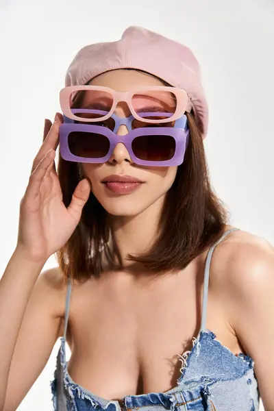 A young, beautiful woman poses confidently in chic attire and colorful sunglasses, radiating style. — Stock Photo