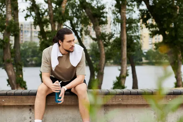Young man enjoys a moment of rest while exercising outdoors near a scenic water view. — Stock Photo