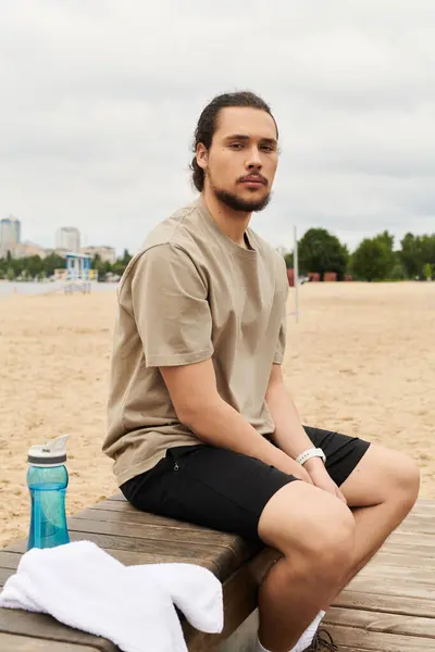 Young man enjoys a moment of relaxation after exercising outdoors by the beach. — Stock Photo