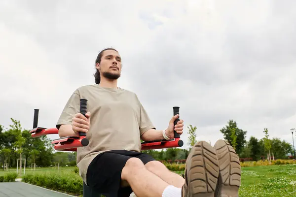 A fit young man with a beard engages in a workout outdoors, focusing on exercise and strength. — Stock Photo