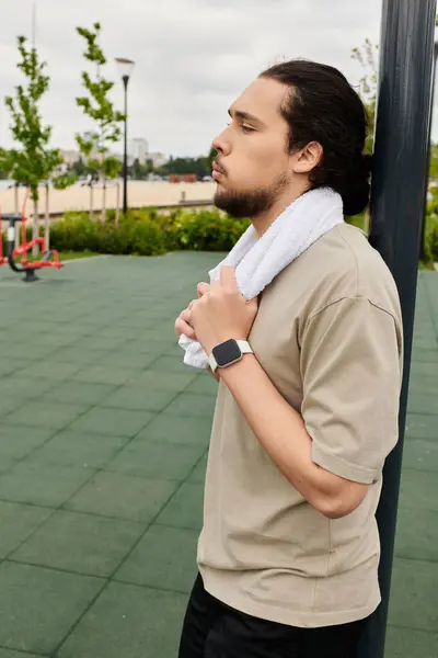 A young man with a beard rests and reflects after an intense outdoor workout session, feeling fit. — Stock Photo