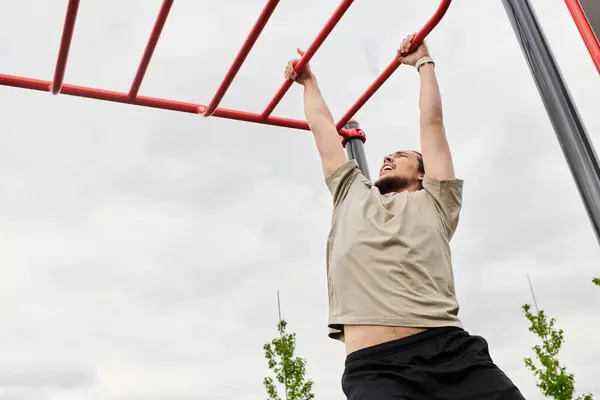 Young sporty man with beard is performing pull-ups at an outdoor fitness area during daylight. — Stock Photo