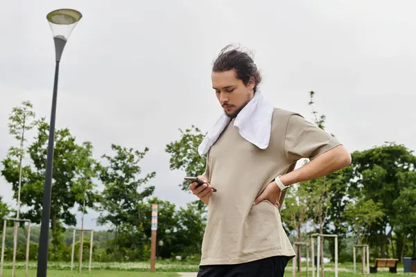 Young man with a beard engages in outdoor exercise, assessing his progress during a workout. — Stock Photo