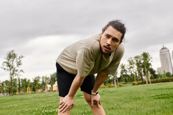 Dedicated young man with a beard exercises in a green park, striving for fitness outdoors. — Stock Photo
