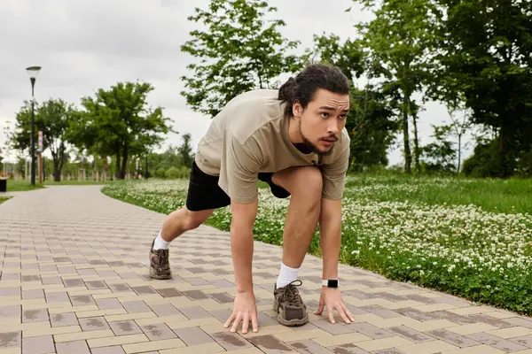 Young man prepares to run, showcasing dedication to fitness in a lush outdoor park. — Stock Photo