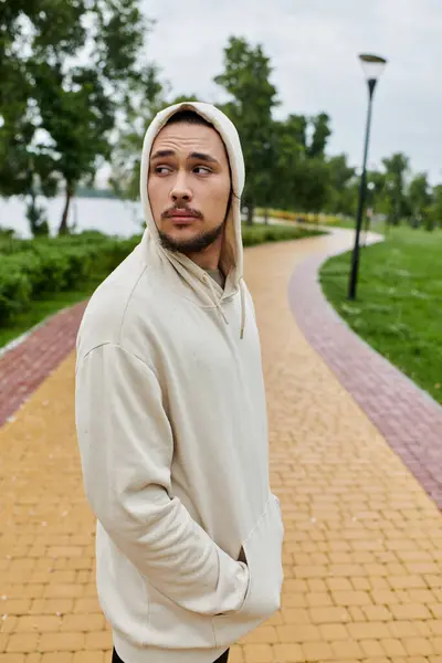 Joven con una sudadera con capucha disfruta de una rutina al aire libre en medio de un entorno tranquilo parque. - foto de stock