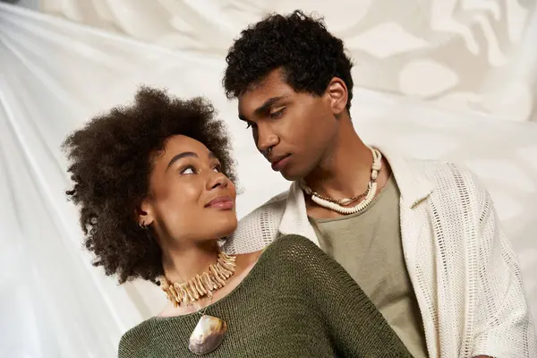 Un jeune couple vêtu à la mode se regarde dans les yeux, rayonnant d'affection et de joie. — Photo de stock