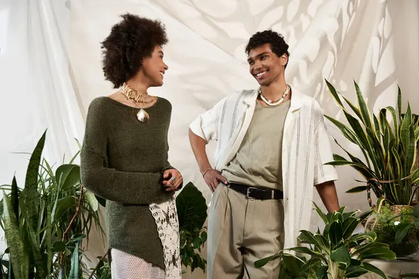A stylish couple shares loving glances among vibrant plants in a warm setting. — Stock Photo