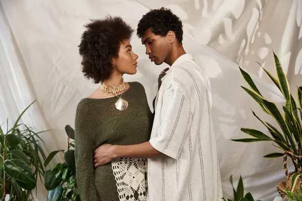 Loving couple gazes into each others eyes, surrounded by lush plants and unique decor. — Stock Photo