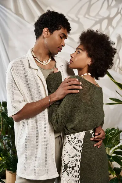 A young couple showcases their love in a cozy embrace amidst vibrant plants, radiating joy. — Stock Photo