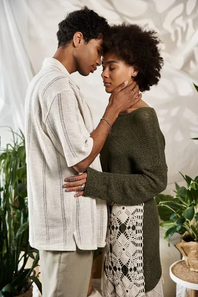 In a cozy space filled with plants, a young couple embraces tenderly, lost in their love. — Stock Photo