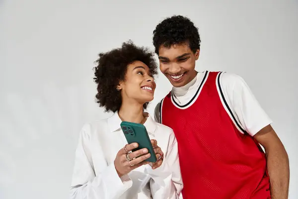 A young couple beams with love as they share a playful moment over their phone. — Stock Photo
