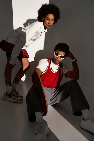 A couple displays their style in a unique pose, bathed in soft light and shadows. — Stock Photo