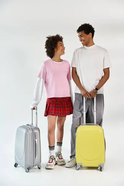 Young couple, bright smiles, ready for travel with their stylish bags in a modern setting. — Stock Photo