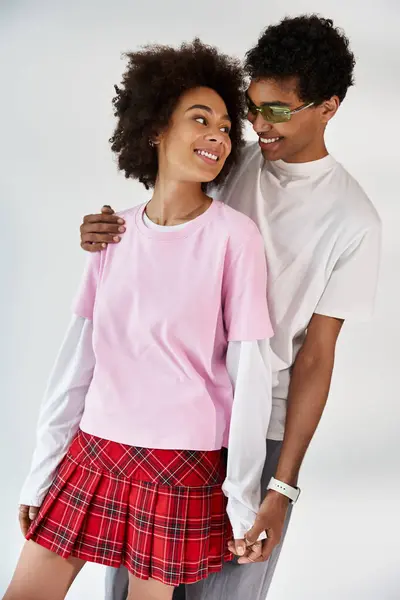 Two young hearts connect over shared laughter, dressed in trendy clothes against a soft backdrop. — Stock Photo