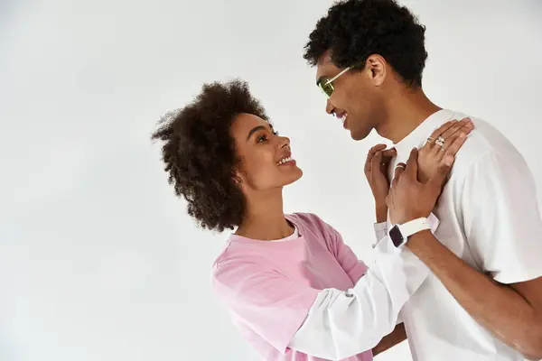 A young couple embraces warmly, exchanging smiles while dressed in chic outfits that radiate love. — Stock Photo