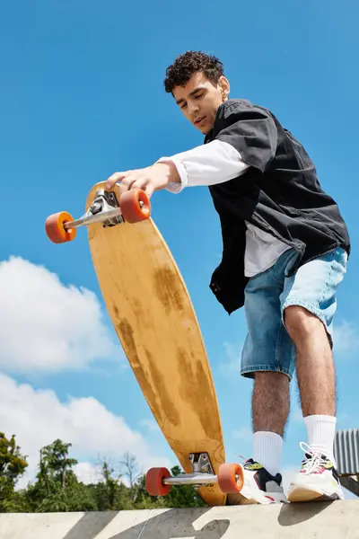 A young man skates at the park under a clear blue sky, showing off his skills on a wooden board. — Stock Photo