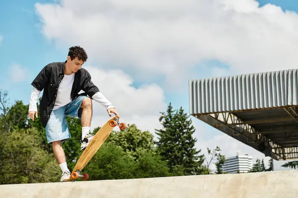 A young man balances on his skateboard, preparing for a trick while surrounded by greenery. — Stock Photo
