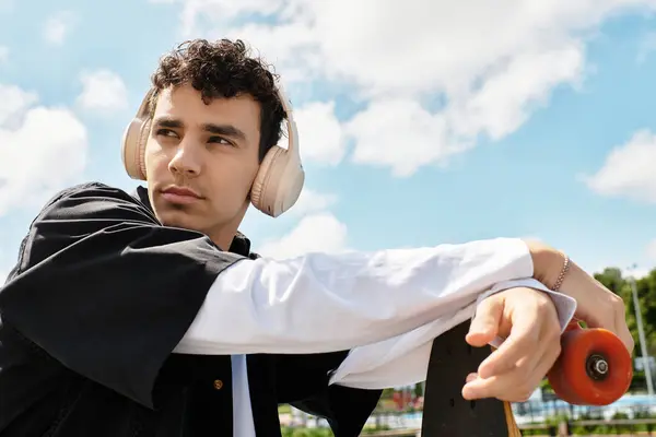 A young man is lost in thought, listening to music and enjoying a peaceful moment at the park. — Stock Photo