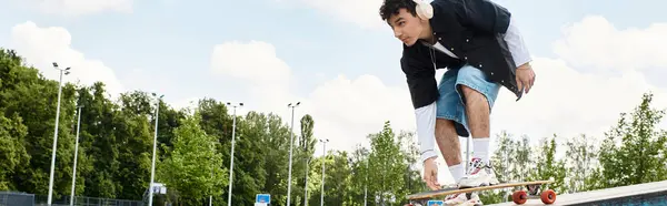 A young man skates quickly in a vibrant park, lost in his groove with headphones on. — Stock Photo