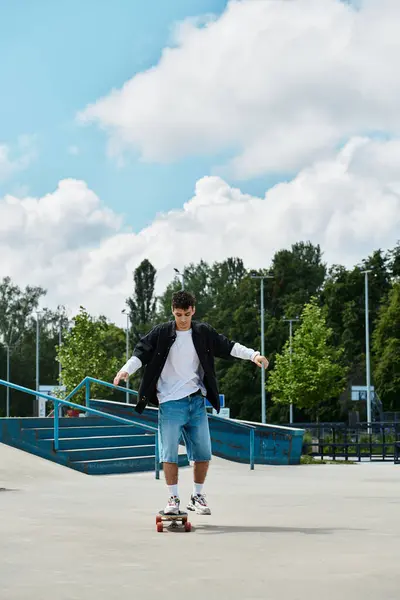 A young man enjoys skateboarding at a lively park surrounded by greenery on a sunny day. — Stock Photo