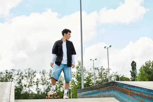 A young man confidently skateboards in a sunny park, surrounded by nature. — Stock Photo