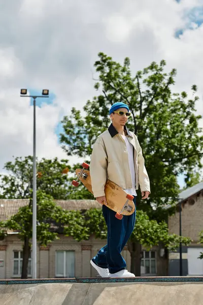A young man strolls through the park with a skateboard, soaking up the sunlight and fresh air. — Stock Photo