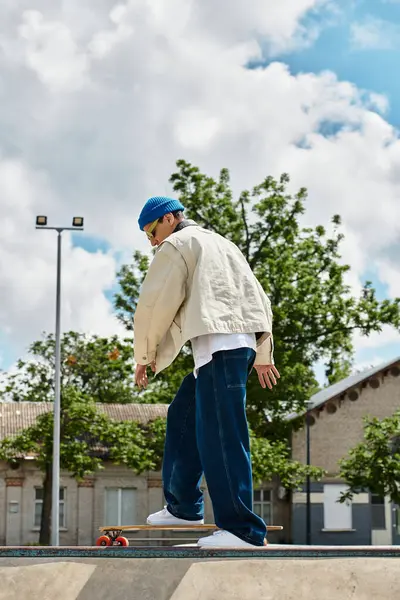 A young man showcases his skateboarding skills in a lively park under a clear blue sky. — Stock Photo