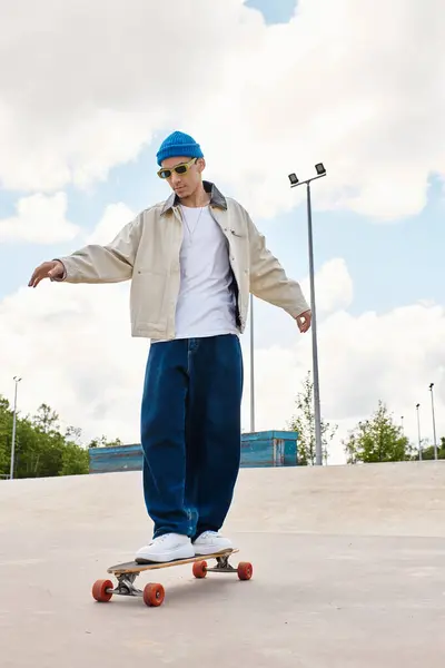 Un joven se equilibra en su monopatín con estilo y confianza en un animado entorno de parque. - foto de stock